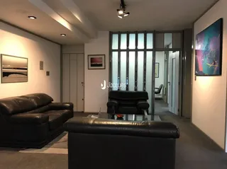 Sala de estar com sofá e pufe de couro escuro.