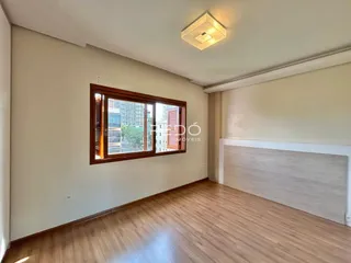 Ambiente interno de uma sala com piso de madeira e janela.