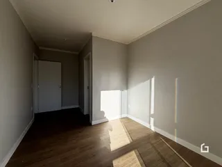 Hall de entrada com piso de madeira escura e paredes claras.