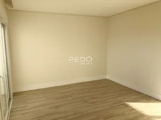 Imagem de uma sala de estar vazia com piso de madeira clara.