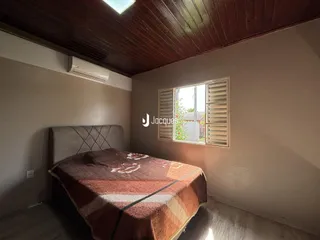 Quarto com teto de madeira e janela com venezianas.
