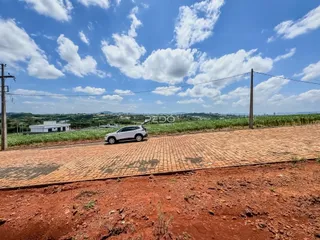 Vista da propriedade com estrada e campo ao fundo.