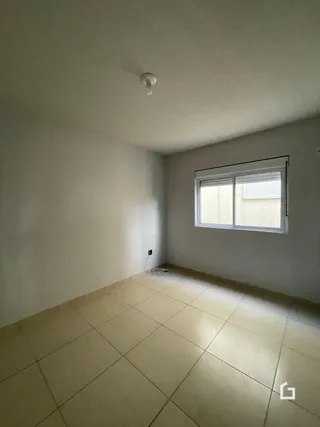 Vista interna de um cômodo com piso de cerâmica e janela.