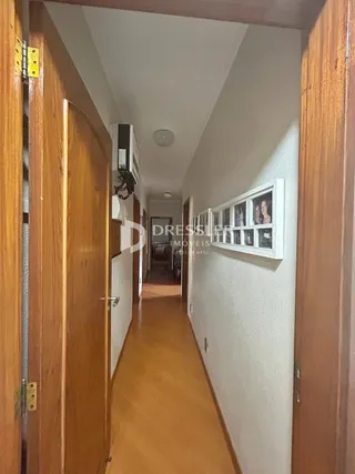 Corredor interno com portas de madeira e piso de madeira.