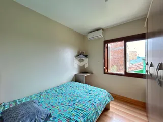 Quarto com cama e janela de madeira.
