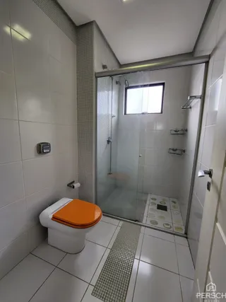 Foto interna de um banheiro com revestimento de azulejos brancos e box de vidro.