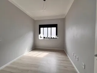 Foto de um cômodo interno com paredes brancas e piso de madeira clara.