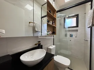 Banheiro com revestimento branco e box de vidro.