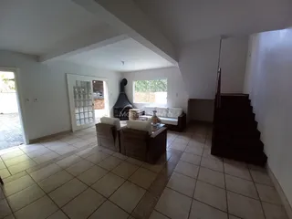 Sala de estar com sofá e poltronas ao redor de uma lareira.