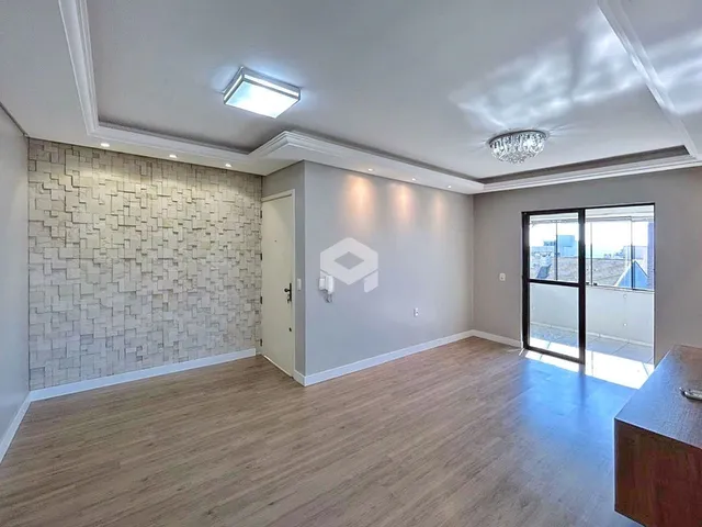 Sala de estar com piso de madeira clara e parede texturizada em um imóvel no Brasil.