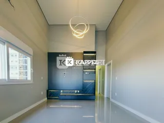Uma sala ampla com pé direito alto e uma área de cozinha planejada escura.