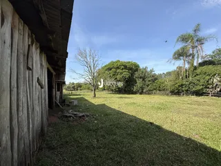 Vista externa da propriedade com um campo gramado e vegetação ao fundo.