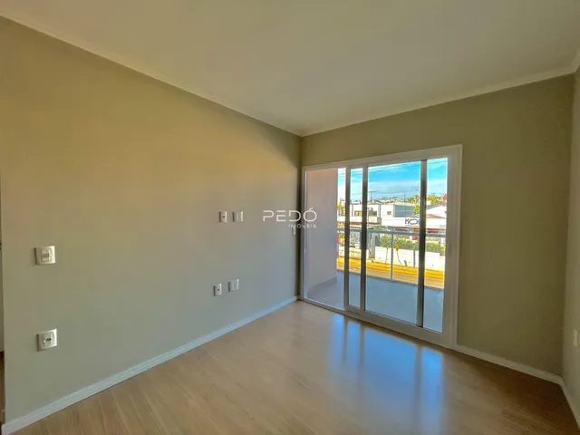 Ambiente interno com piso de madeira e porta de vidro que dá para a área externa.