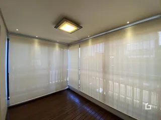 Foto de um cômodo interno com piso de madeira e grandes janelas.