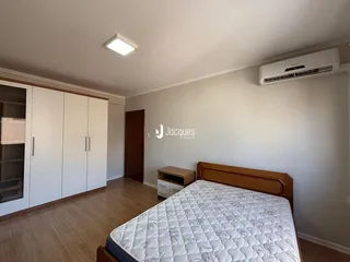 O quarto apresenta piso de madeira e armários embutidos nas paredes.