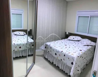 Quarto com cama de casal coberta com lençóis brancos e cortinas brancas.