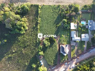 Vista aérea de uma propriedade rural com plantações de videiras e residências adjacentes.
