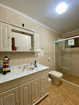 Banheiro com revestimento de cerâmica e box de vidro transparente.