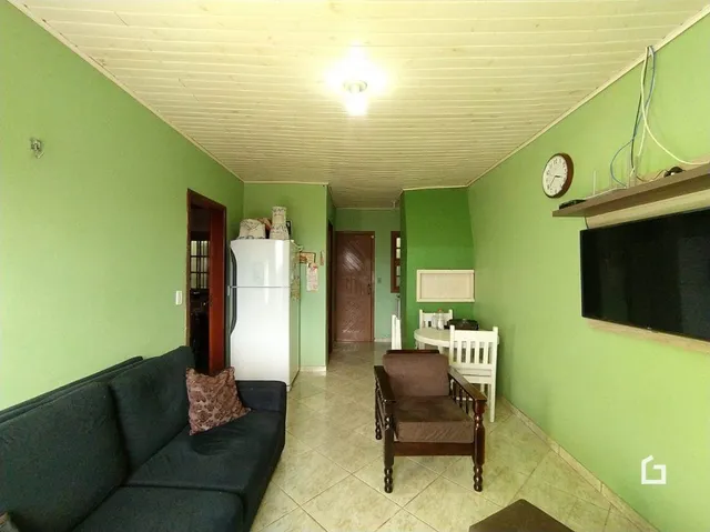 Sala com sofá e geladeira branca na residência.