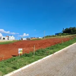 Vista externa de um terreno com terra vermelha e estrada no primeiro plano.