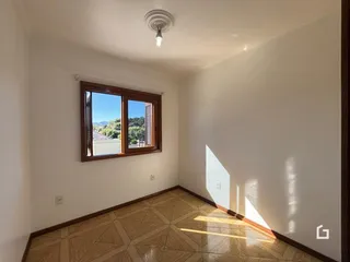 Vista interna de uma sala com piso de cerâmica e janela.