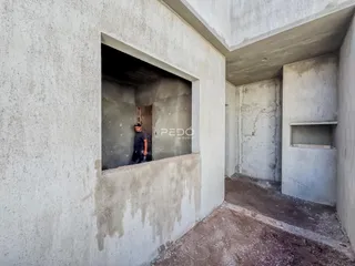 Foto de um corredor interno com paredes de concreto cru em uma propriedade.