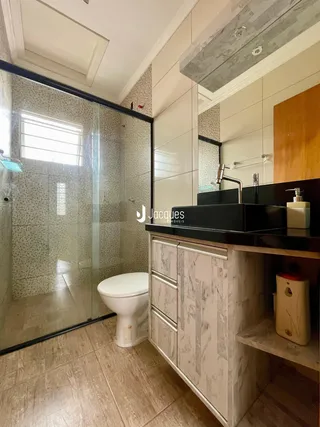 Foto de um banheiro moderno com box de vidro e revestimentos claros.