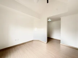 Interior de uma sala com piso de madeira clara e paredes brancas.
