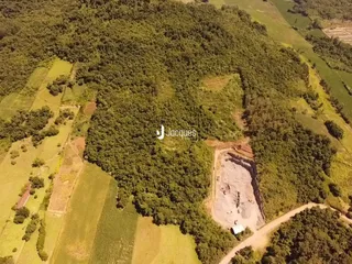 Vista aérea de uma área rural com vegetação densa e campos abertos.