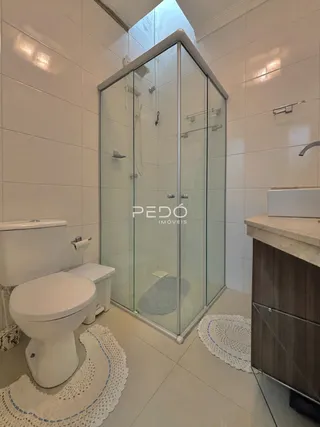 Foto do interior de um banheiro com box de vidro e vaso sanitário.