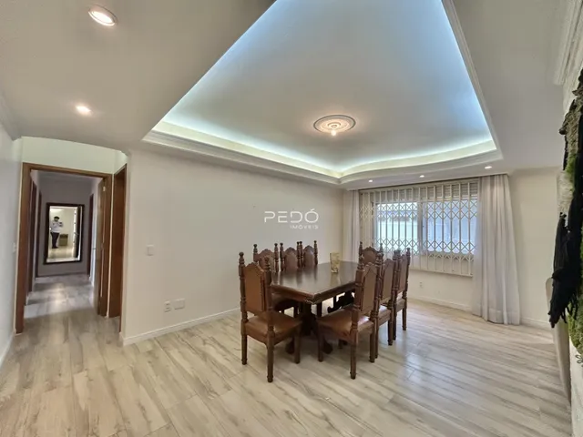 Uma sala de jantar com mesa de madeira e piso claro.