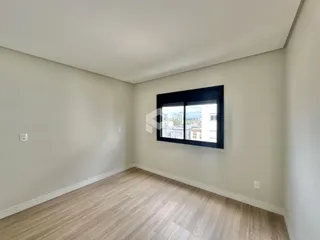 Ambiente interno de uma sala com piso de madeira clara e janela grande.