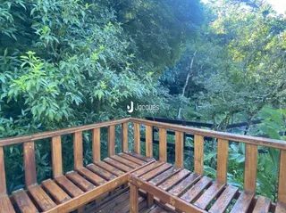 Guarda-corpo de madeira de uma varanda com vista para a vegetação.