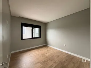 Ambiente interno com paredes cinzas e piso de madeira clara.