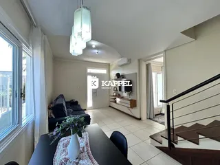 Sala de estar com sofá e luminária pendente em um apartamento no Brasil.