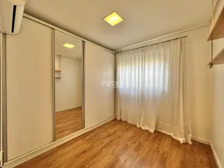 Quarto com piso de madeira e portas espelhadas em uma sala de Lajeado.