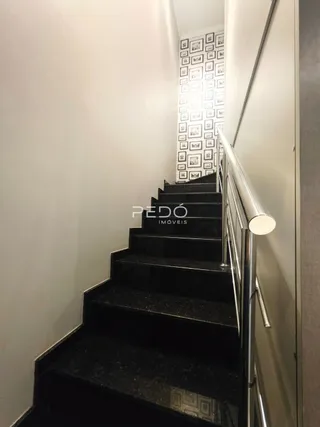 Foto de uma escadaria interna com corrimão metálico.