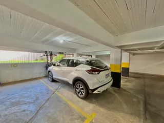 Um carro branco está estacionado em uma área coberta de concreto.