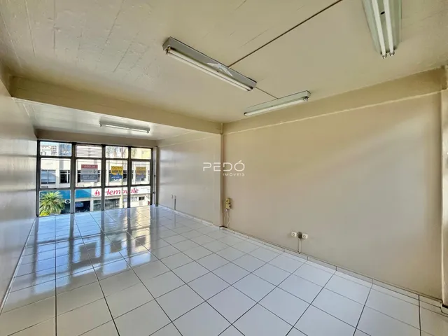 Corredor longo com piso de cerâmica e paredes brancas em um imóvel.