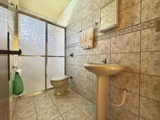Foto interna de um banheiro com revestimento de azulejos claros e um vaso sanitário.