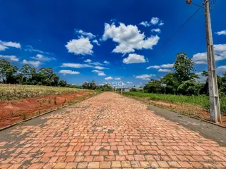 Uma estrada de tijolos vermelhos atravessa um campo aberto sob um céu azul.