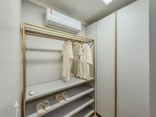 Um armário com prateleiras douradas exibindo roupas e sapatos.