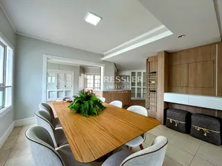 Uma sala de jantar com mesa de madeira e cadeiras em um ambiente claro.