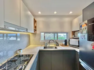 Cozinha moderna com armários brancos e bancadas claras.