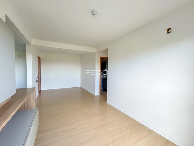 Ambiente interno de uma sala ampla com piso de madeira clara.