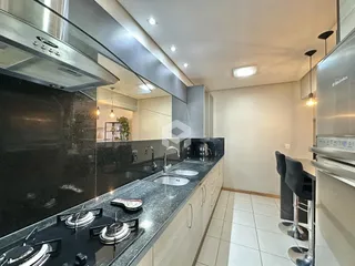 Cozinha moderna com bancadas escuras e armários claros.