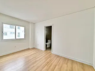 Uma sala de estar com piso de madeira clara e uma janela grande.