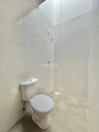 Foto de um banheiro com azulejos brancos e vaso sanitário.