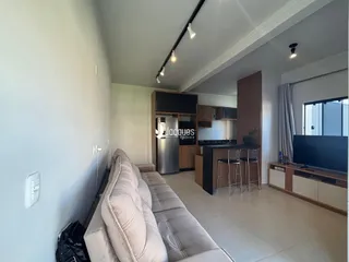 Sala de estar moderna com sofá e área de jantar em um apartamento.