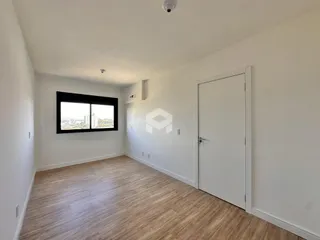 A sala de estar possui piso de madeira clara e uma grande janela com vista para a cidade.